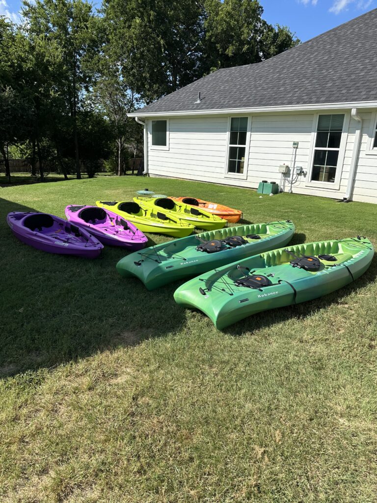 kayaks on the grass in multiple colors